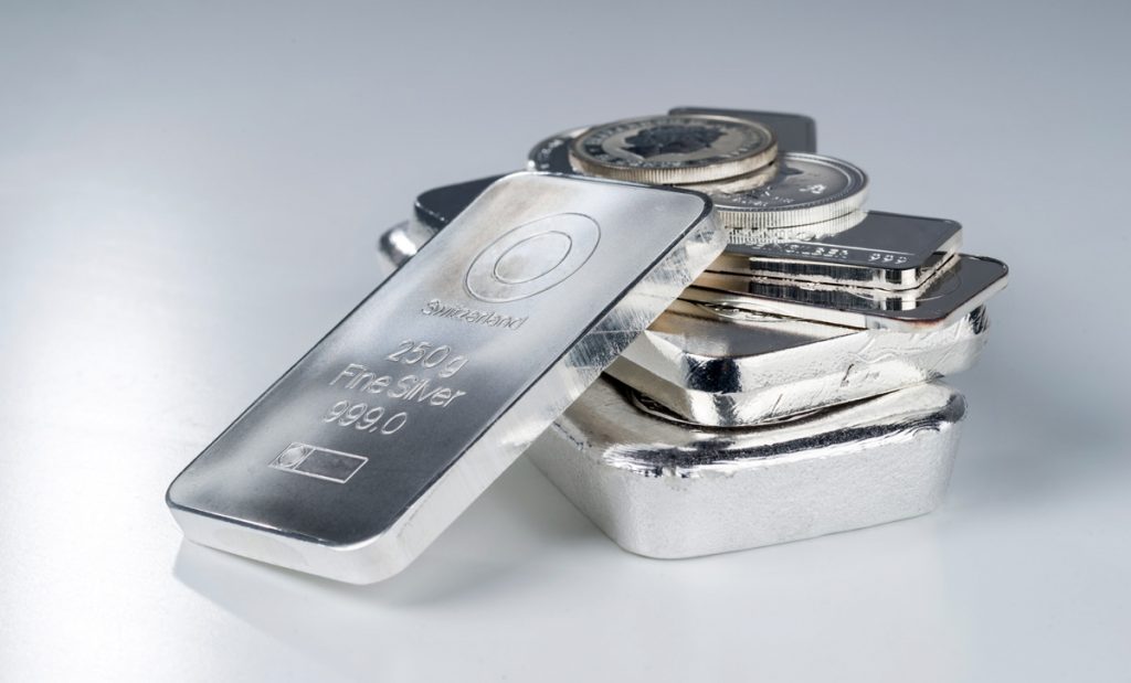 Silver bullion. Cast and minted bars and coins on a gray backgro